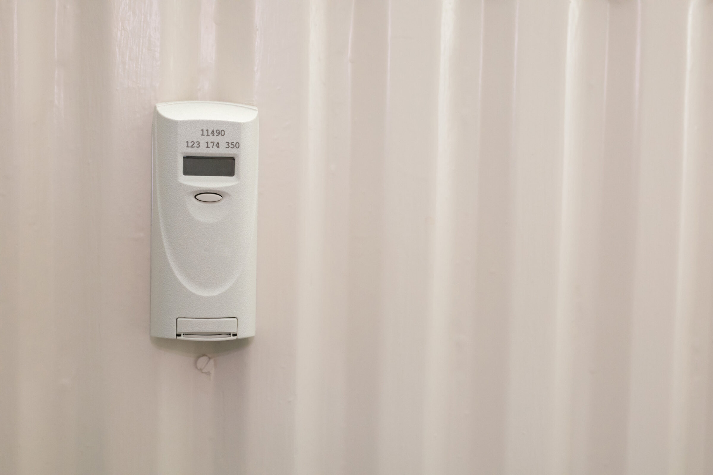 Heizkostenverteiler: Nahaufnahme eines Heizkoerpers. Auf der linken Bildseite ist ein elektronischer Heizkostenverteiler montiert, dessen Display nicht eingeschaltet ist.